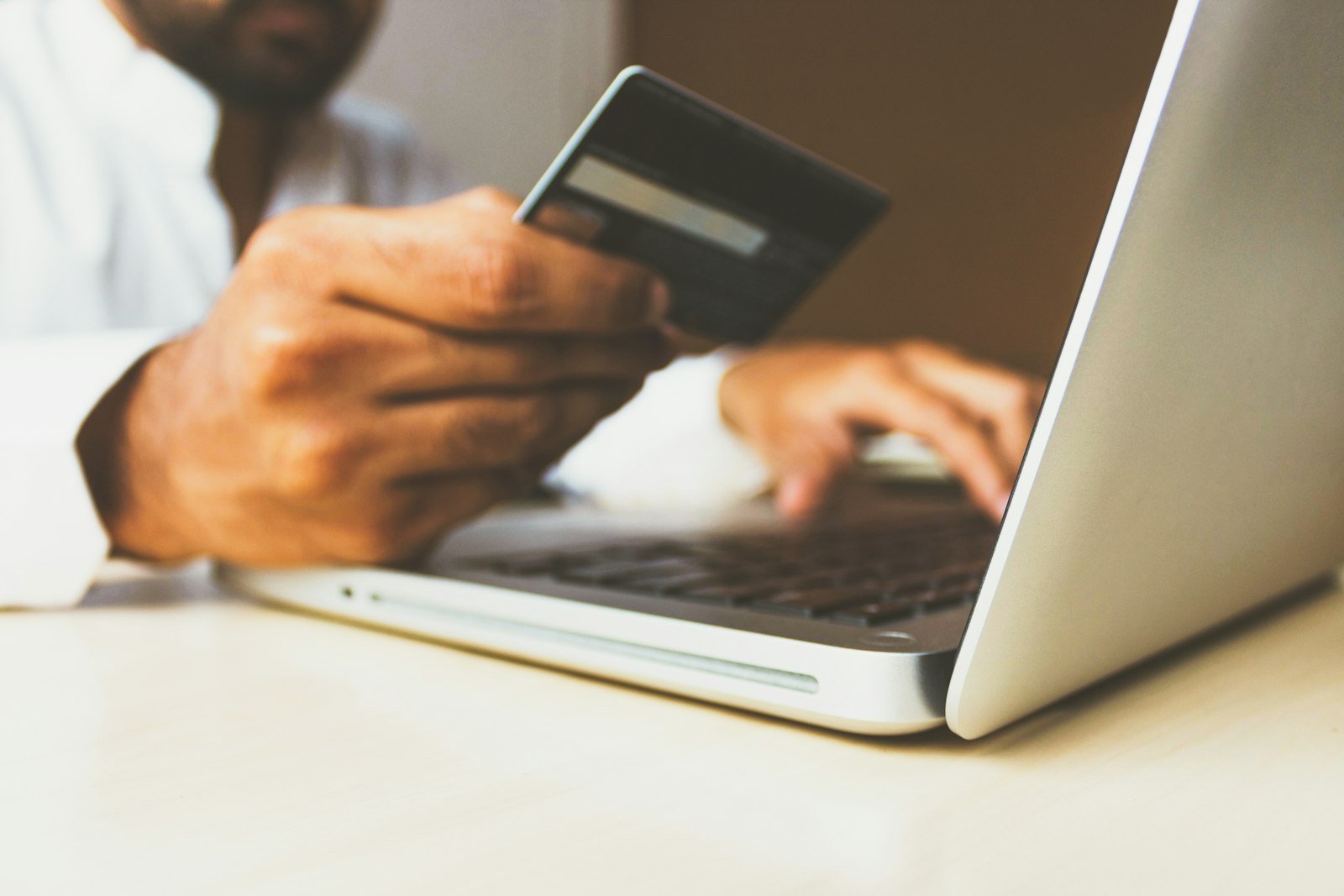 Person shopping online on a laptop holding a payment card
